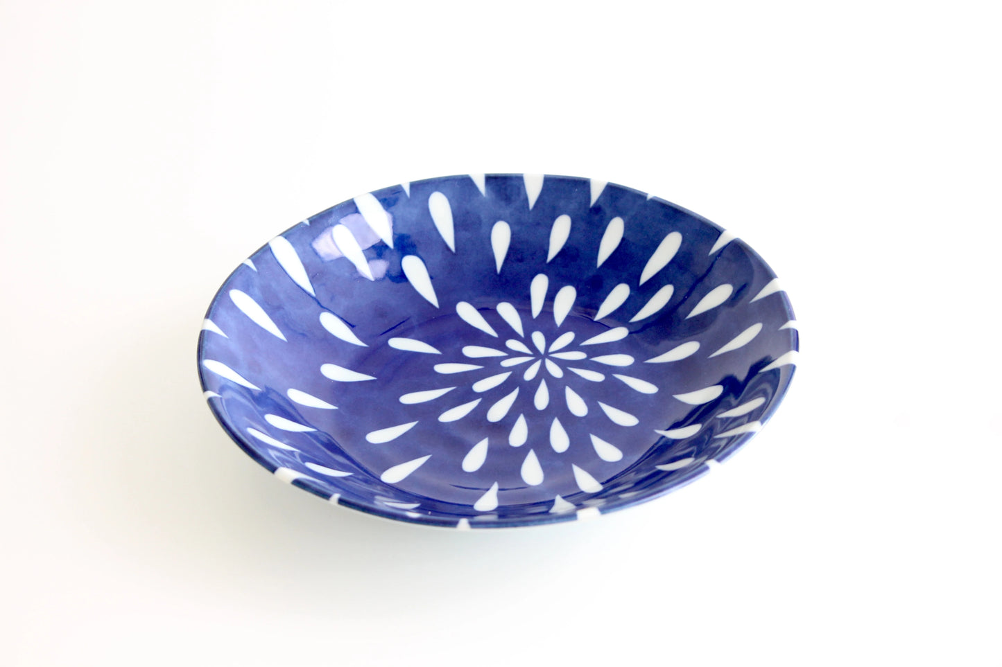 Elegant indigo ceramic curry plate with a white chrysanthemum motif, inspired by Japanese craftsmanship.