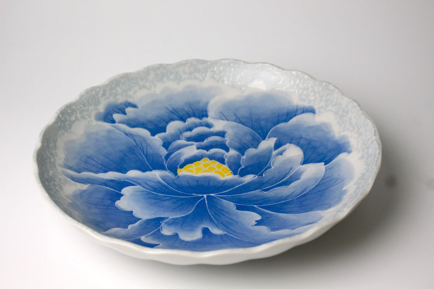 Dining plate featuring an intricate peony flower design with a wavy, textured edge for improved grip.