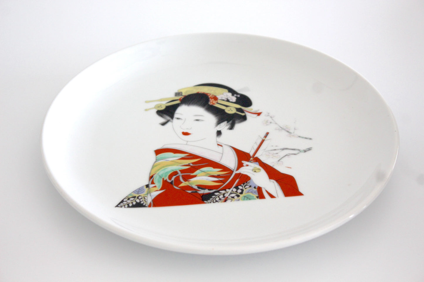 11-inch porcelain dinner plate featuring an elegant geisha in a red kimono, adorned with intricate cherry blossom accents, microwave-safe.
