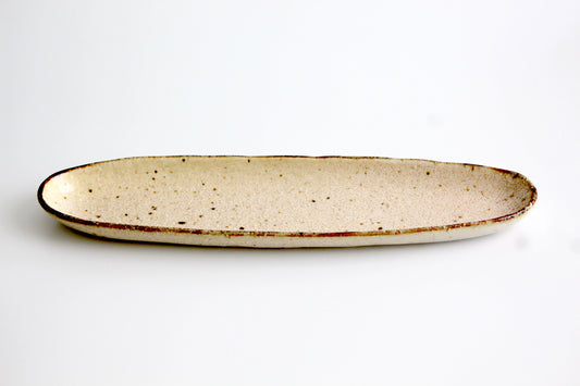 Handcrafted boat-shaped snack plate with an earthy speckled glaze, perfect for serving appetizers, sushi, or desserts.