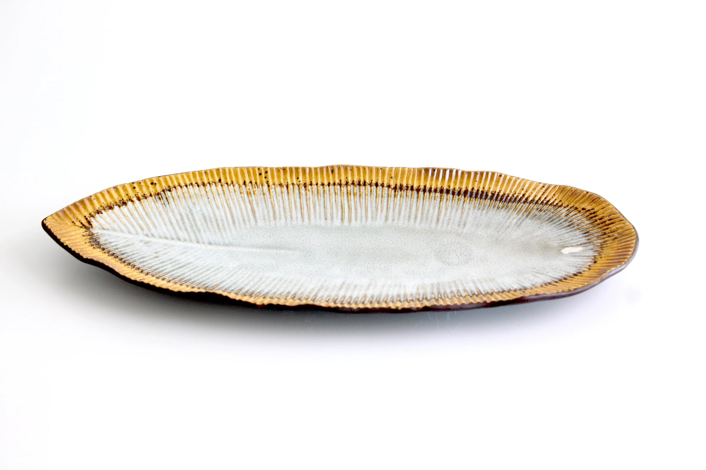 Elegant ceramic platter inspired by a golden leaf, featuring a textured rim with a white glazed center, perfect for serving appetizers or desserts.