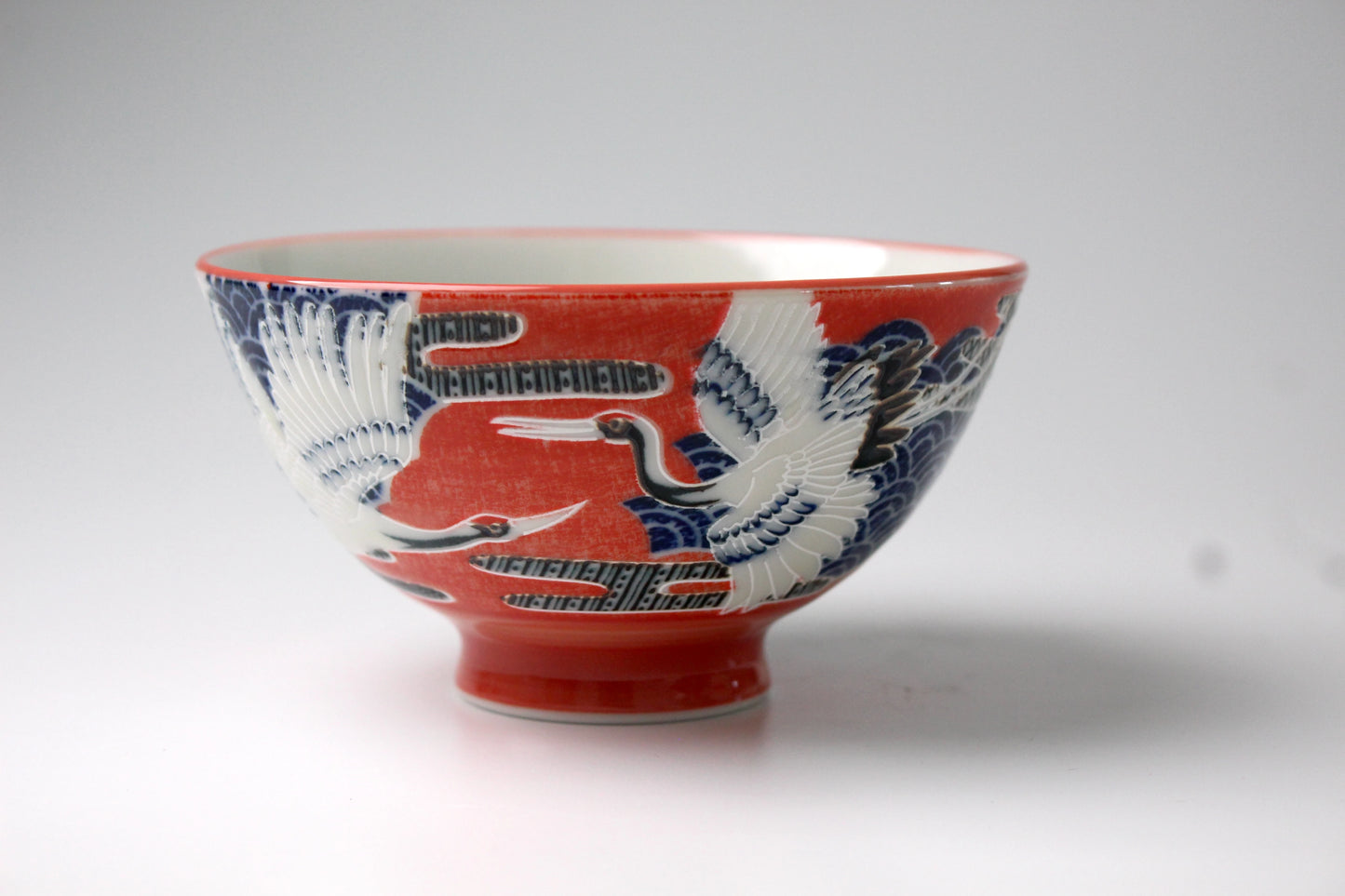 Japanese rice bowl featuring an elegant design of red-crowned cranes in flight against a vibrant red and blue background, symbolizing longevity and good fortune.