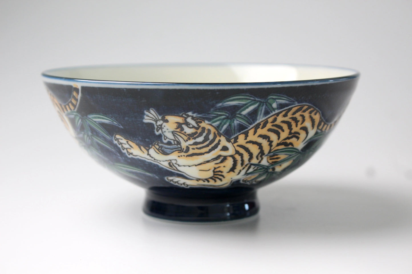 Traditional Japanese rice bowl with a vibrant blue background featuring an intricate hand-painted tiger design, symbolizing strength and courage.
