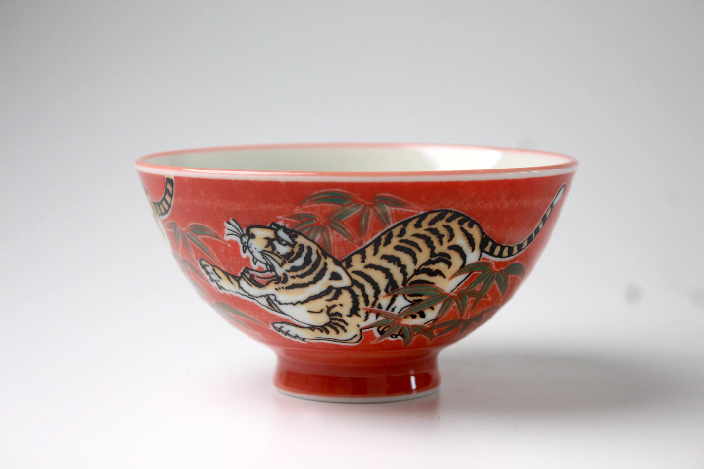 Traditional Japanese rice bowl with a vibrant red background featuring an intricate hand-painted tiger design, symbolizing strength and courage.