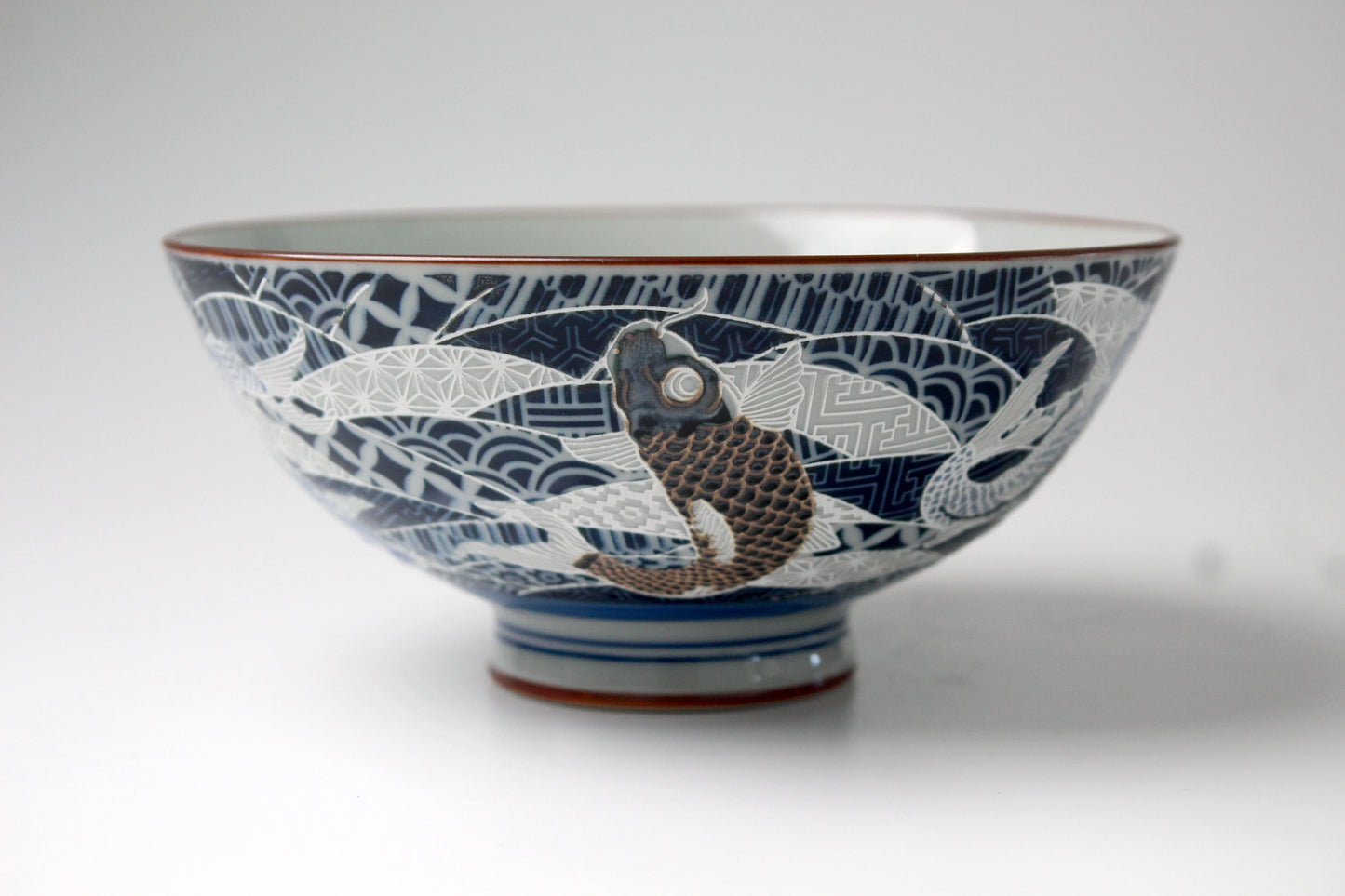 A beautifully crafted Japanese rice bowl featuring intricately etched koi fish on the exterior, finished with a glossy and smooth glaze.
