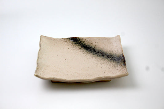 Handmade ceramic snack plate with a speckled, textured glaze resembling a black Milky Way. Features a wavy rim designed to hold chopsticks. Elegant and artisanal design.
