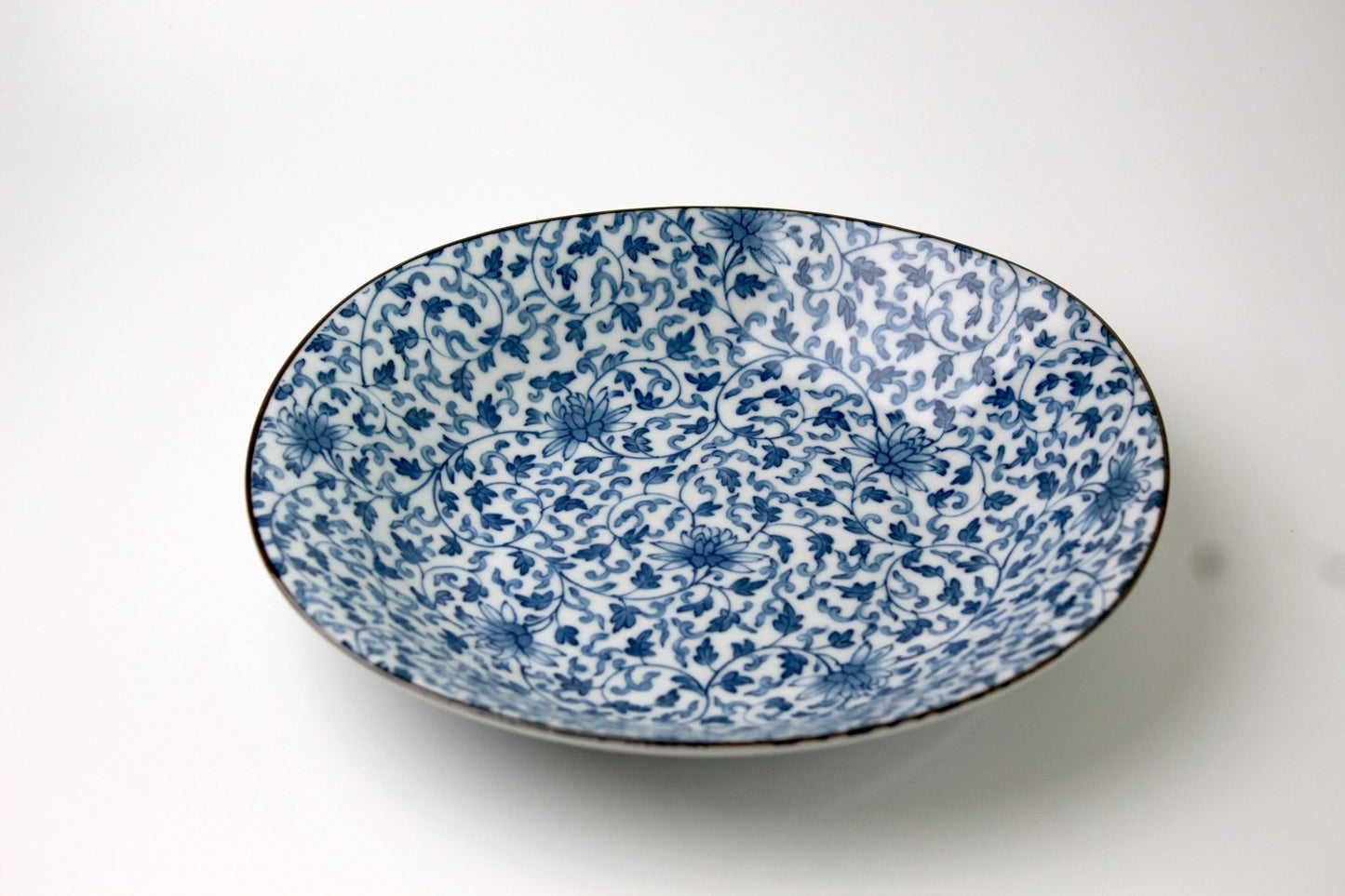 A Japanese porcelain plate in Saikai style, featuring intricate floral network