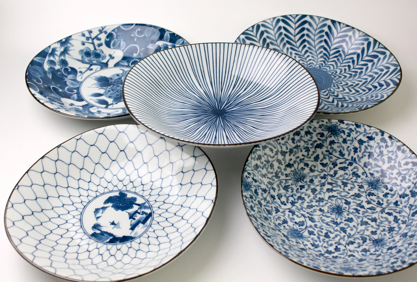 A set of five Japanese Saikai-style dining plates with intricate blue and white patterns, inspired by traditional Arita and Imari porcelain