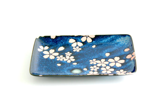 A beautifully crafted ceramic snack plate featuring a deep blue glaze with delicate sakura (cherry blossom) etchings, inspired by a night sky. Perfect for serving sushi, appetizers, or desserts.
