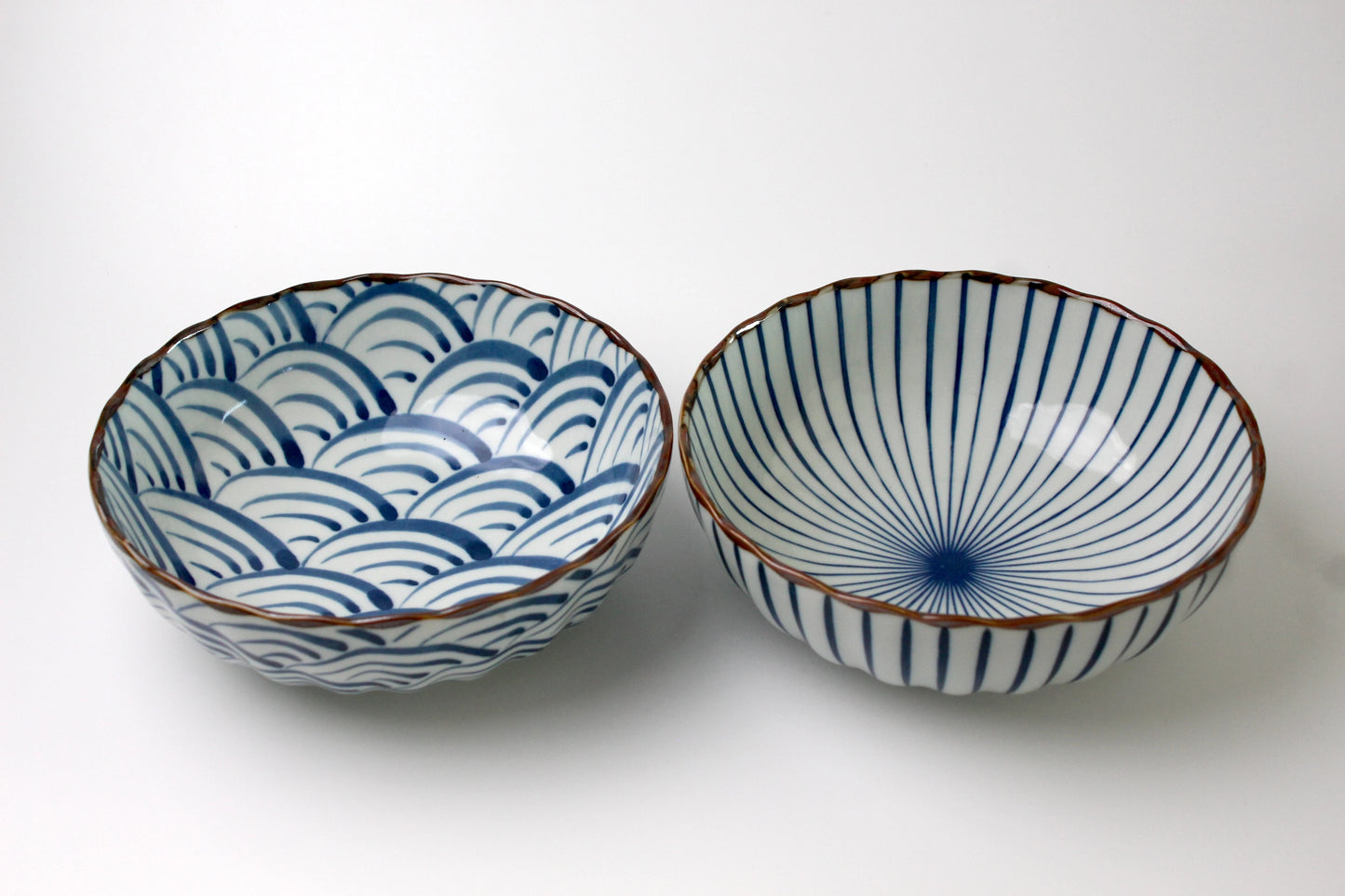A pair of Japanese ceramic bowls featuring traditional Seigaiha (blue ocean waves) and Sensu (fan) patterns with a scalloped rim and a glossy finish.