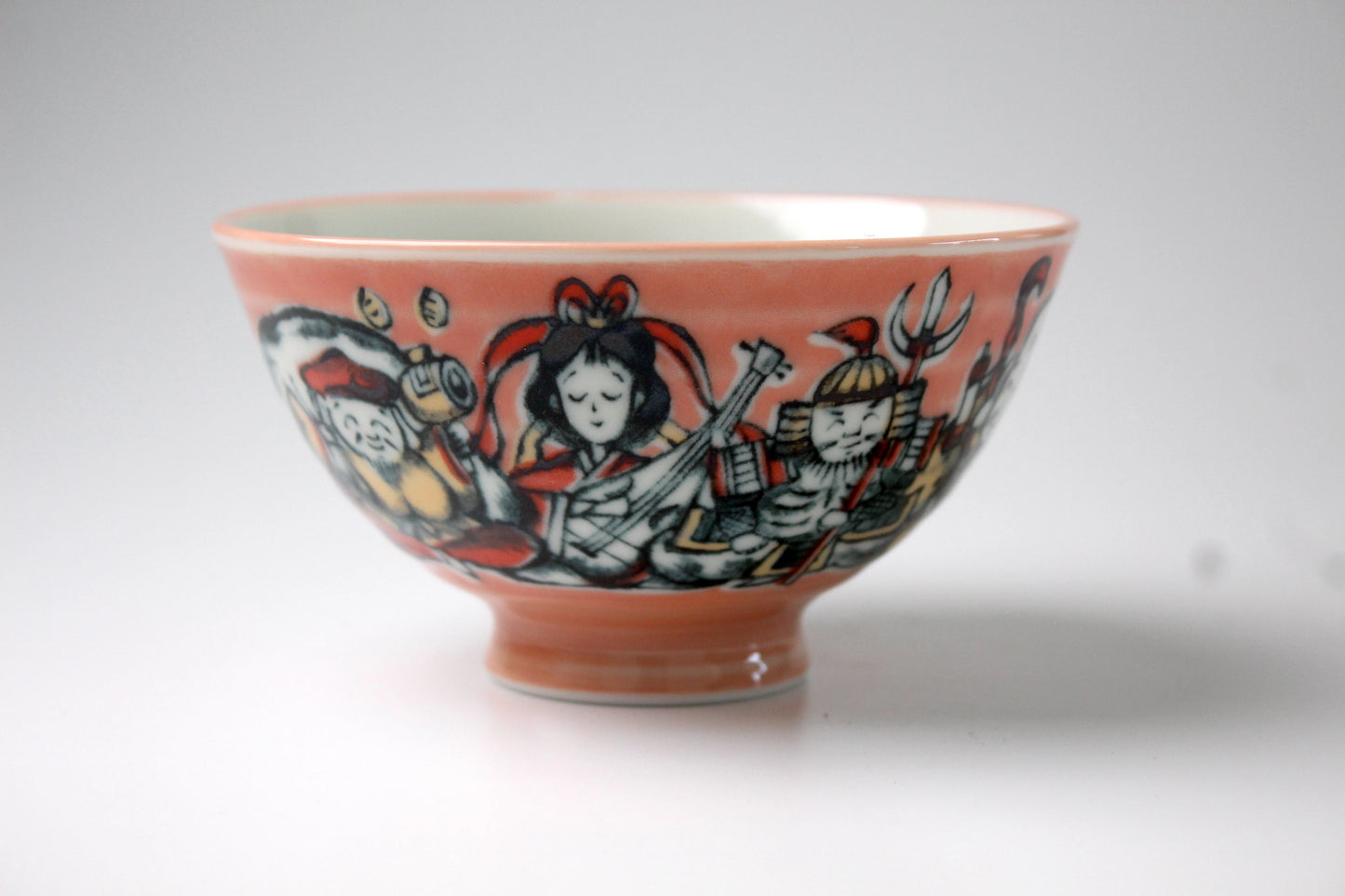 Japanese rice bowl featuring the Seven Gods of Fortune, beautifully illustrated in traditional colors on a soft coral background.
