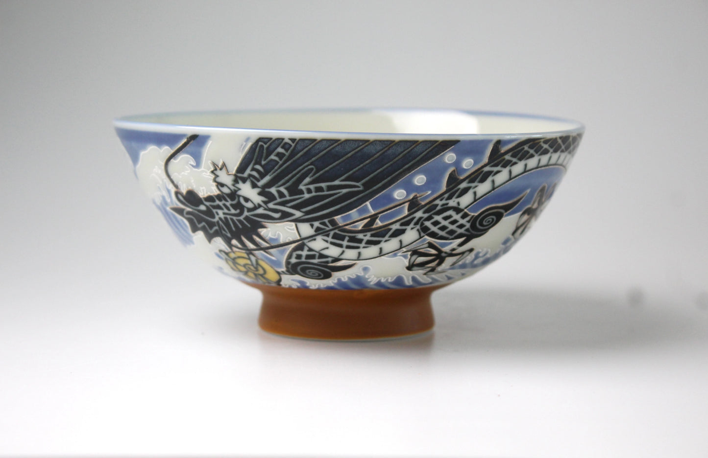 A ceramic rice bowl featuring an intricately etched wave dragon design with a glossy, smooth finish, perfect for serving rice or small portions.