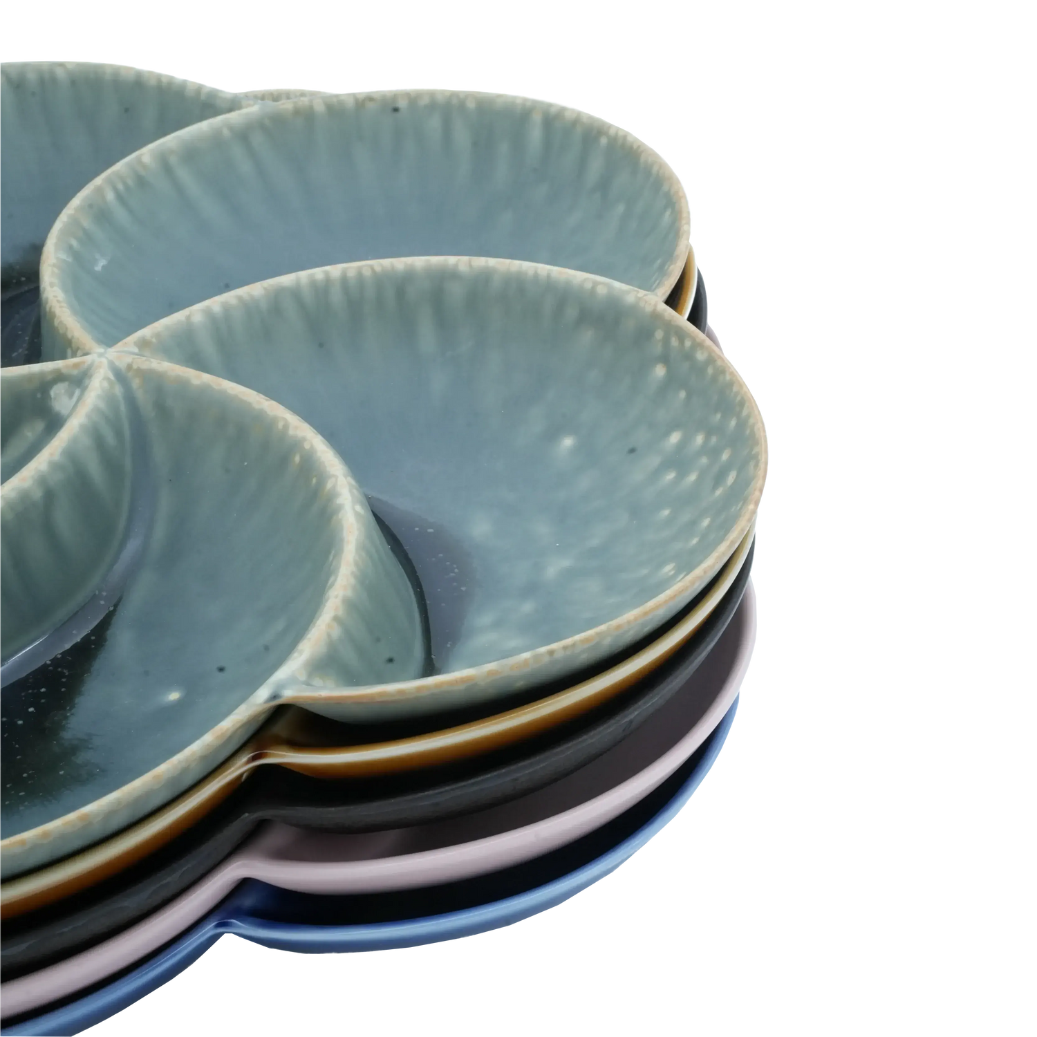Stack of colorful ceramic dining plates with textured surface on a light blue background