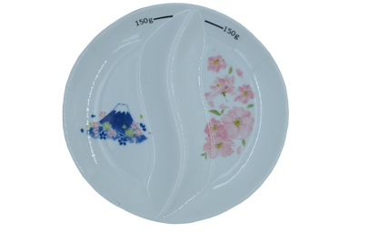 Top-down view of a white two sectional thali or divided plate with 150g markings, featuring Mount Fuji & cherry blossoms designs