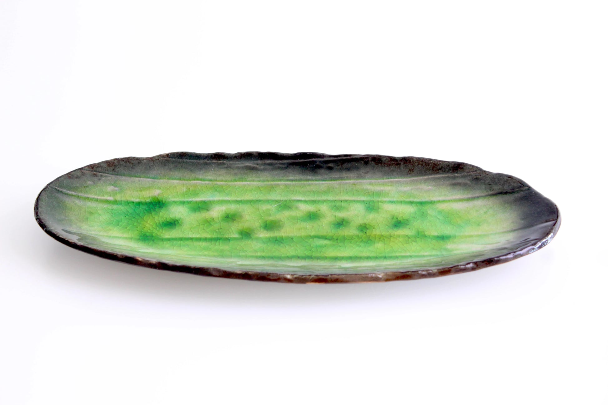 A handcrafted ceramic snack platter with a glossy leaf green glaze, featuring a textured banana leaf design and earthy brown edges.