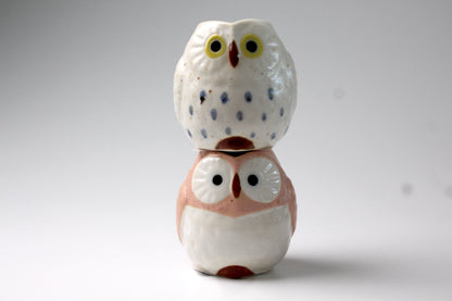 White & pink ceramic owls shaped milk pitchers. The owls are sitting on top of each other.