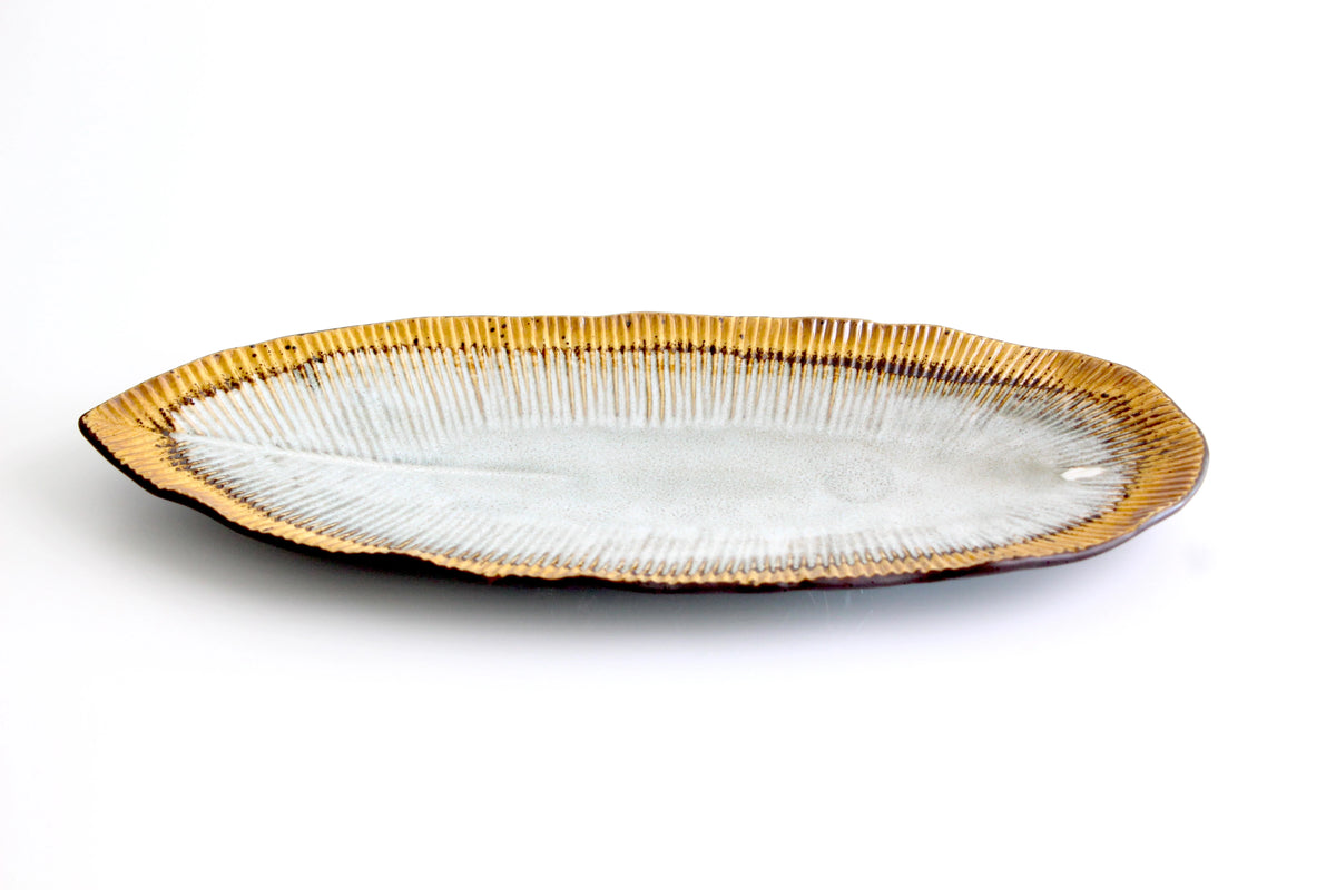Elegant ceramic platter inspired by a golden leaf, featuring a textured rim with a white glazed center, perfect for serving appetizers or desserts.