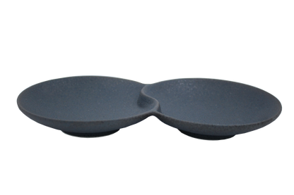 An isometric view of the Missera Hotate, a matte black ceramic divided serving dish with two circular sections joined in the center like a clam shell. Perfect as a multi compartment serving dish for snacks and dips.