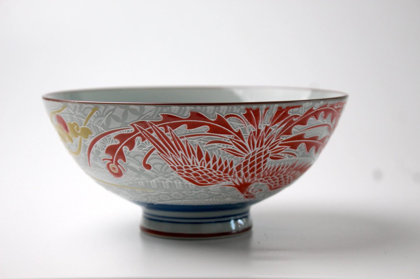 A beautifully crafted ceramic rice bowl with an intricately etched red phoenix design on the exterior, featuring a glossy finish.